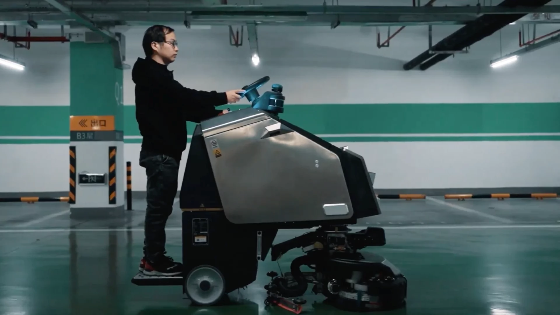 Image of man standing on a step attached to the back of cleaning robot, Scrubber 75